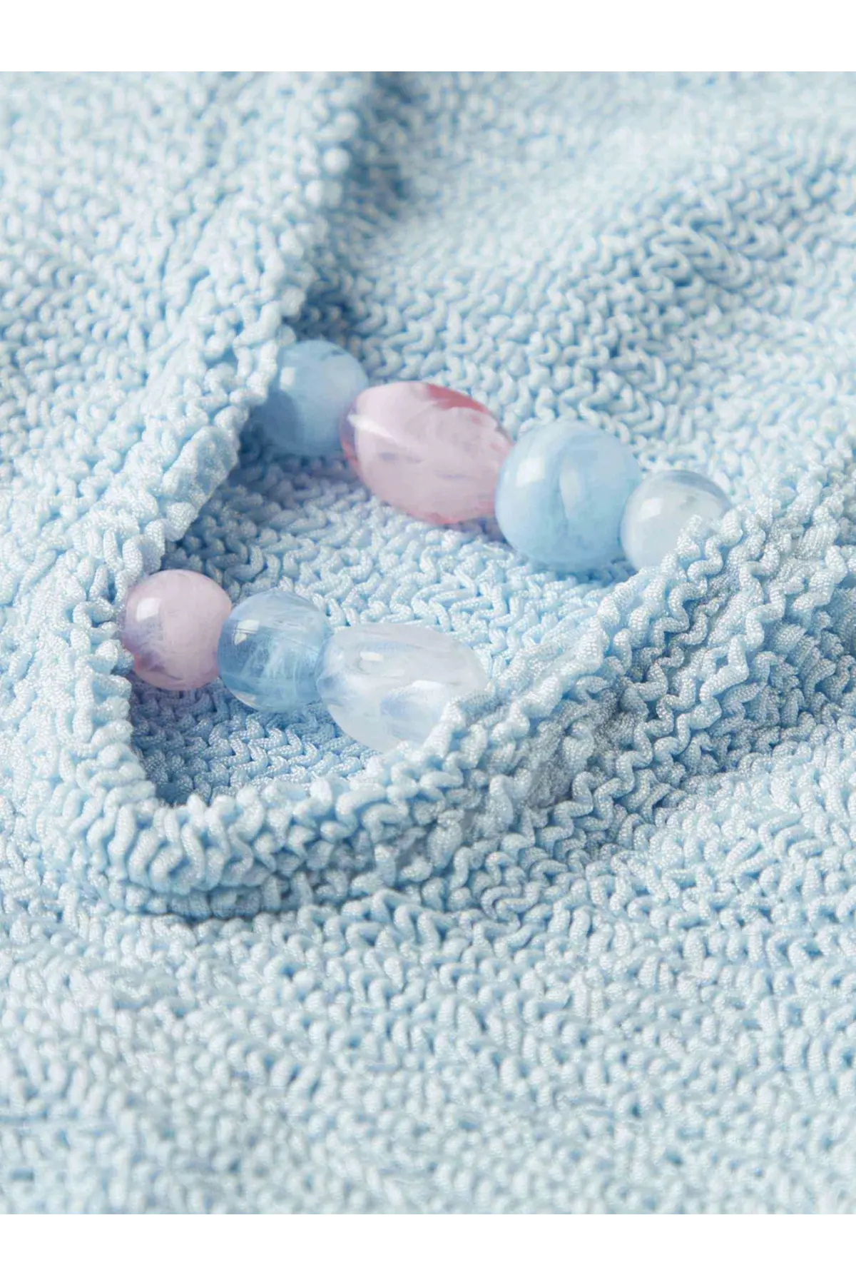 A delicate bracelet of smooth translucent beads in pastel blue and pink complements hunza g womens adriana swimsuit