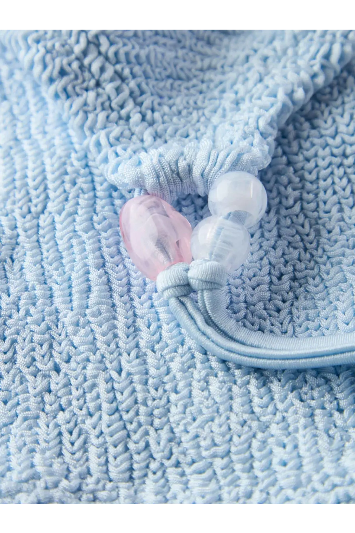 Hunza G women’s cassie the original crinkle bikini blue with a delicate light blue knitted drawstring bag and bead accent