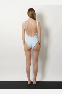 A light blue Hunza G women’s one-piece swimsuit in crinkle fabric with thin straps and a deep back cutout shown from the back