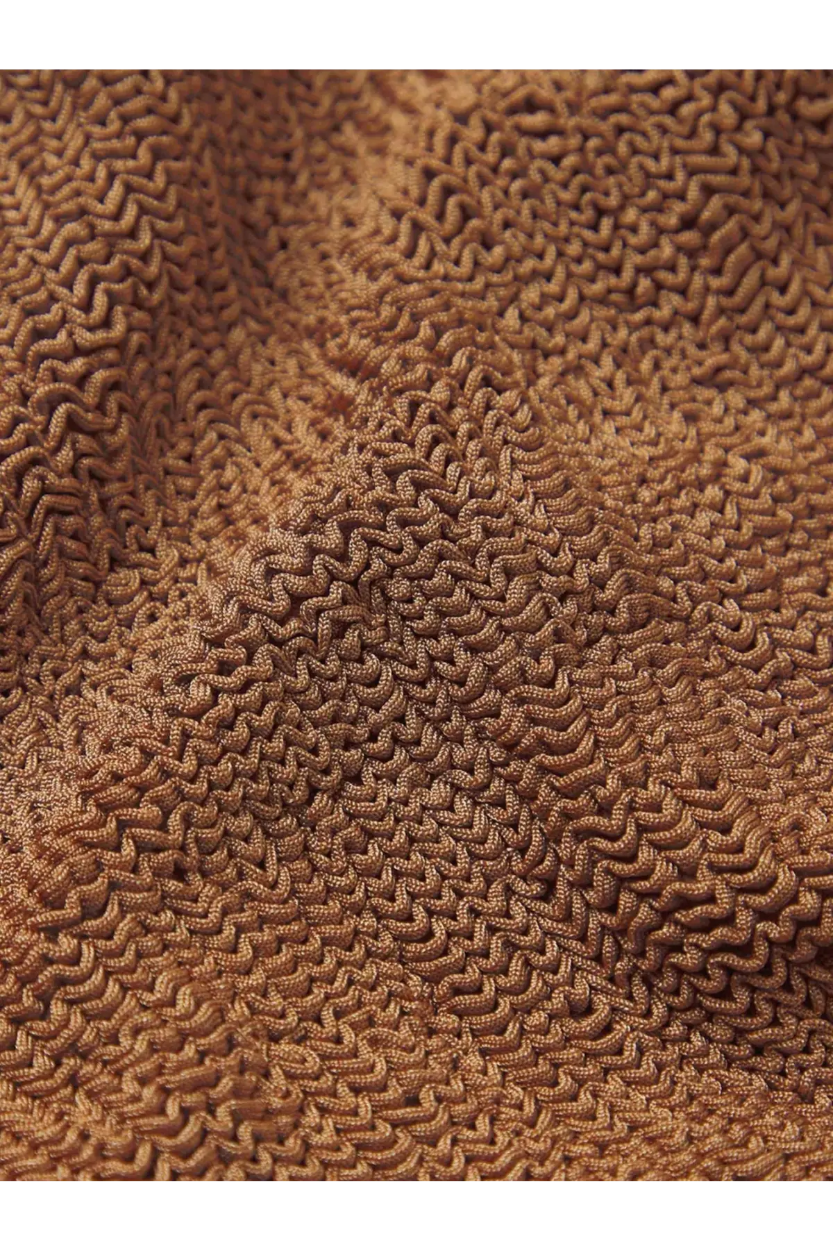 A close-up of a brown textured towel with a wavy looped knit pattern for hunza g women’s crinkle fabric one piece swimsuit