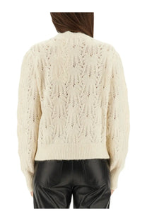 Cream-colored intricately knitted sweater with textured back pattern and ribbed cuffs shown from the back side