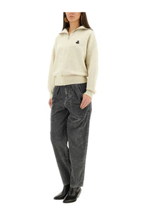 Cream-colored zip-up sweater with small black embroidered logo on left chest paired with Isabel Marant Étoile black pants