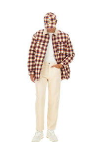 A man wearing an Isabel Marant men’s jacket steeve multicolor over a brown and beige plaid flannel shirt with cream trousers