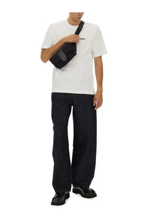 Black crossbody bag with sleek minimalist design and subtle branding paired with Jacquemus men’s blue denim pants