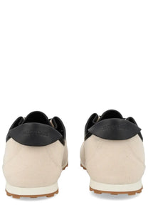 Beige canvas jacquemus men’s sneaker les tennis white with black leather accents and white rubber sole viewed from the back