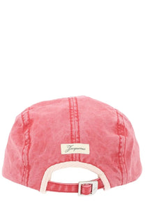 Pink denim five-panel cap by jacquemus with white fabric strap silver buckle and beige label visible on the back side