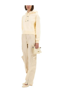 Cream-colored leather mini clutch with minimalist design and metallic hardware paired with jacquemus the grosgrain hoodie beige