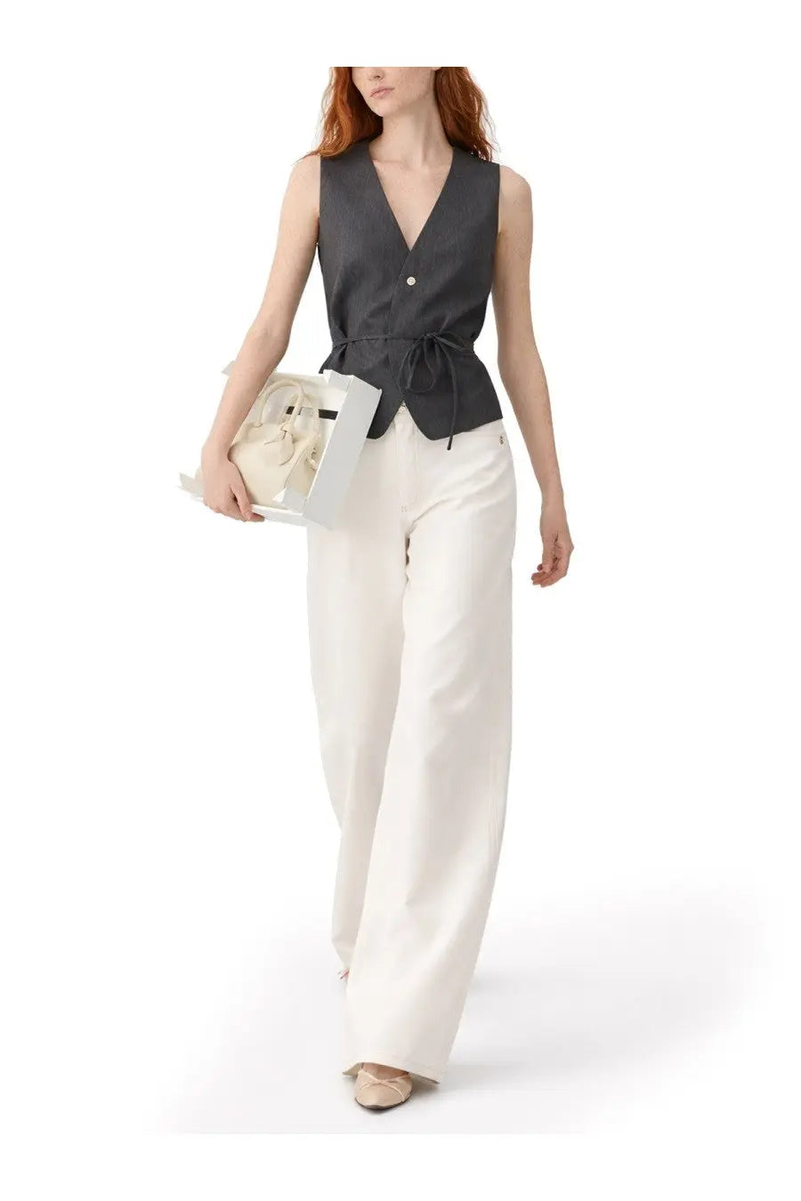 The model wears a sleek dark gray sleeveless button-up vest with a v-neck and tied waistband in jacquemus jeans ovalo white
