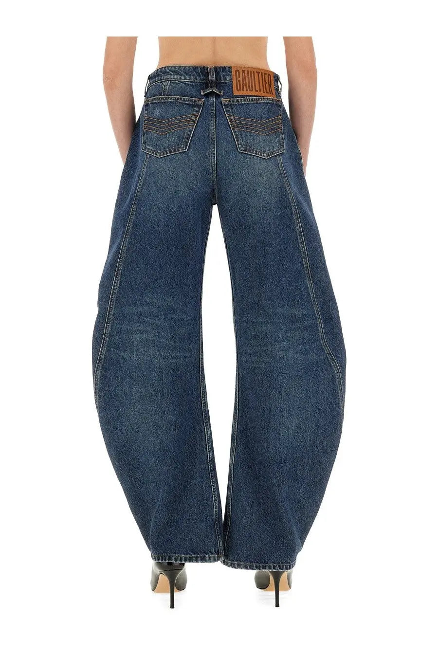 Dark blue denim jean paul gaultier women’s low rise wide-leg jeans with brown leather brand patch at waistband back view
