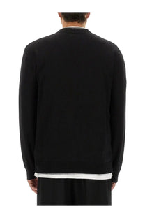 Black jil sander men’s merino wool cardigan with ribbed crew neckline and cuffs worn over white collared shirt