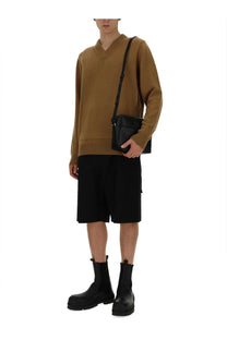 Black leather crossbody bag with minimalist design and adjustable strap paired with jil sander men’s beige neck sweater