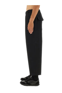 Jil Sander men’s black tapered trousers with wide-leg relaxed fit and asymmetrical flap pocket detail