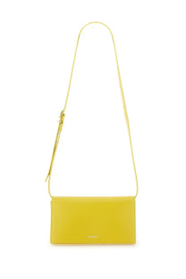 A sleek mustard-yellow leather crossbody bag with minimalist design and slender adjustable strap by Jil Sander
