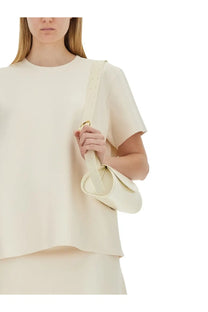Cream-colored leather crossbody bag with gold-tone hardware and minimalist design paired with jil sander pink shirt