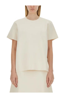 Cream-colored jil sander women’s boxy fit shirt with short sleeves and subtle asymmetrical hem in minimalist style
