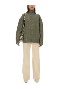 Olive green oversized turtleneck sweater with textured knit and ribbed cuffs paired with jil sander white flared pants