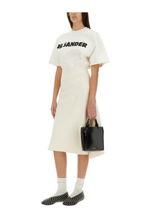 Black glossy mini tote bag with top handles and small metallic logo shown with jil sander women’s white shirt