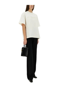Black leather mini tote bag with gold-tone hardware paired with jil sander women’s white shirt