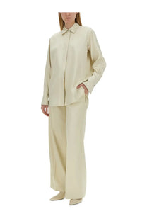 Cream-colored silk blouse with structured collar and long sleeves paired with jil sander women’s tailored white pants