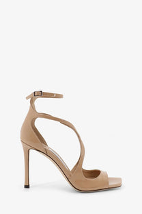 Beige patent leather strappy high heel sandal with slender stiletto heel and ankle strap by Jimmy Choo women’s Azia