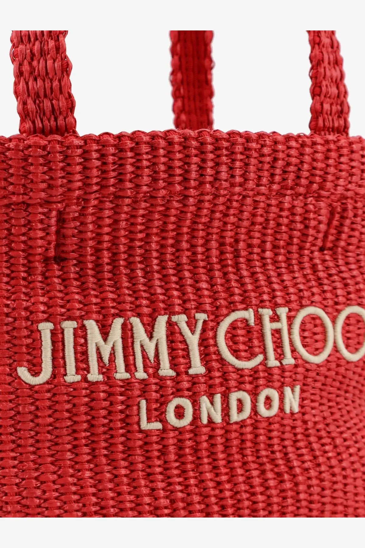A vibrant red woven raffia crossbody tote bag featuring the jimmy choo london logo in cream embroidery