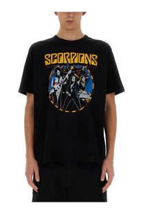 Black short-sleeved junya watanabe man shirt featuring vibrant scorpions band graphic with yellow lettering