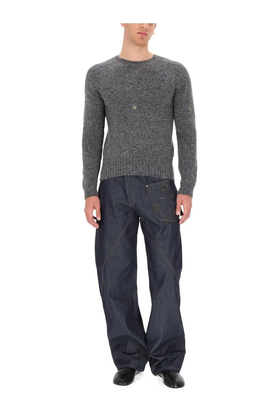 Back view of jw anderson men’s jersey grey dark blue denim pants with diagonal seam and large logo patch on pocket