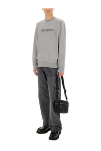 Black crossbody bag with sleek minimalist design and silver hardware shown with jw anderson men’s grey sweatshirt
