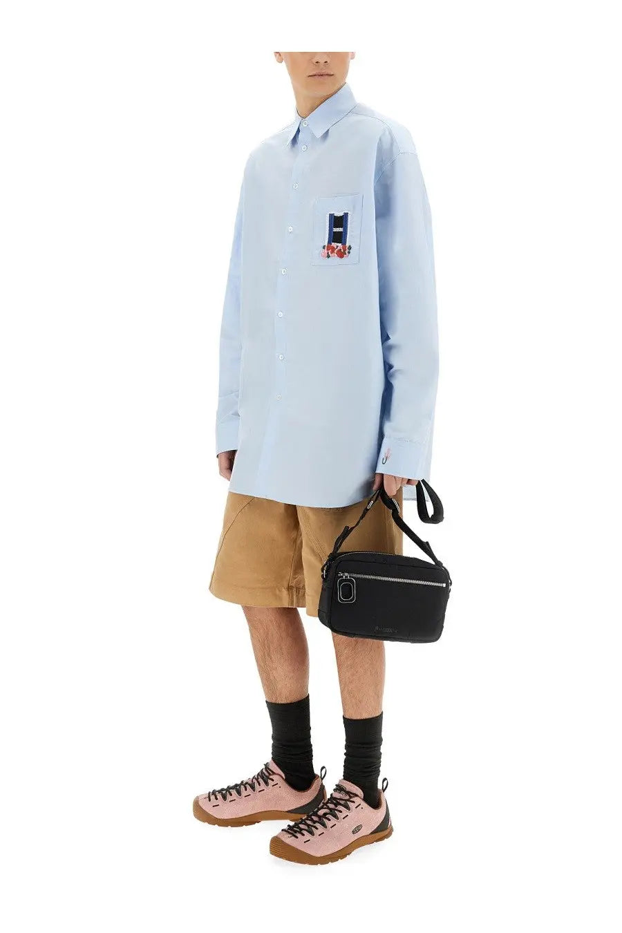 Black crossbody bag with silver zipper and circular logo detail complementing jw anderson men’s blue window shirt