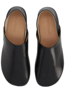 Jw anderson women’s black leather slipper shoe featuring a minimalist design and smooth glossy finish
