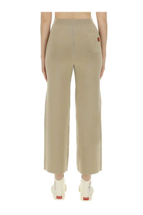Beige knit wide-leg kenzo women’s pants with ribbed waistband and small orange logo patch on the back pocket shown from behind
