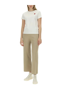 White short-sleeved t-shirt with small red embroidered apple on left chest paired with kenzo women beige pants
