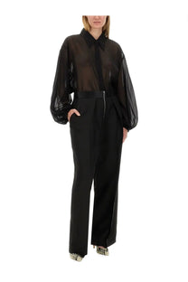 Khaite women’s pants the marine black paired with a black sheer blouse featuring voluminous sleeves and a structured collar