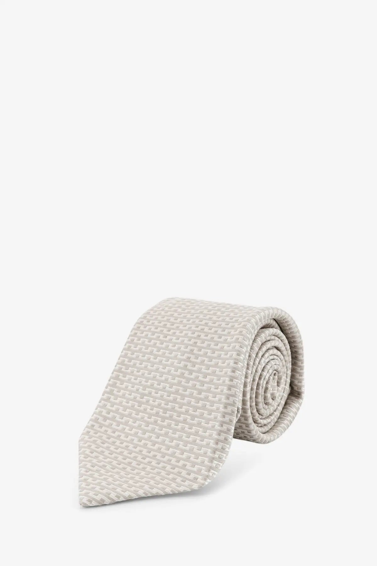 A neatly rolled beige Kiton men’s silk tie with a subtle woven texture and multicolor design