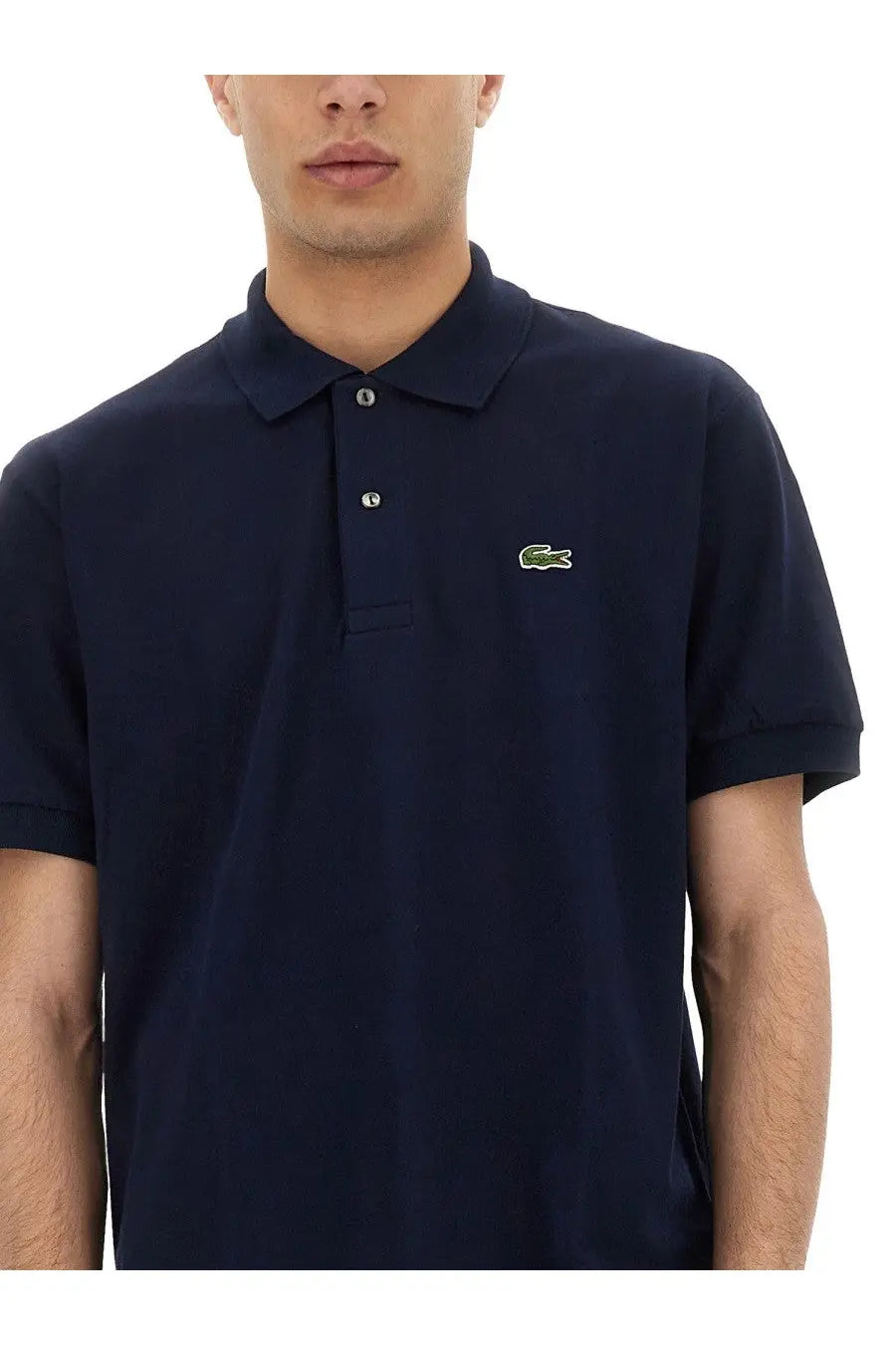 Navy blue Lacoste men’s polo shirt featuring a green crocodile logo and silver buttons on the left chest