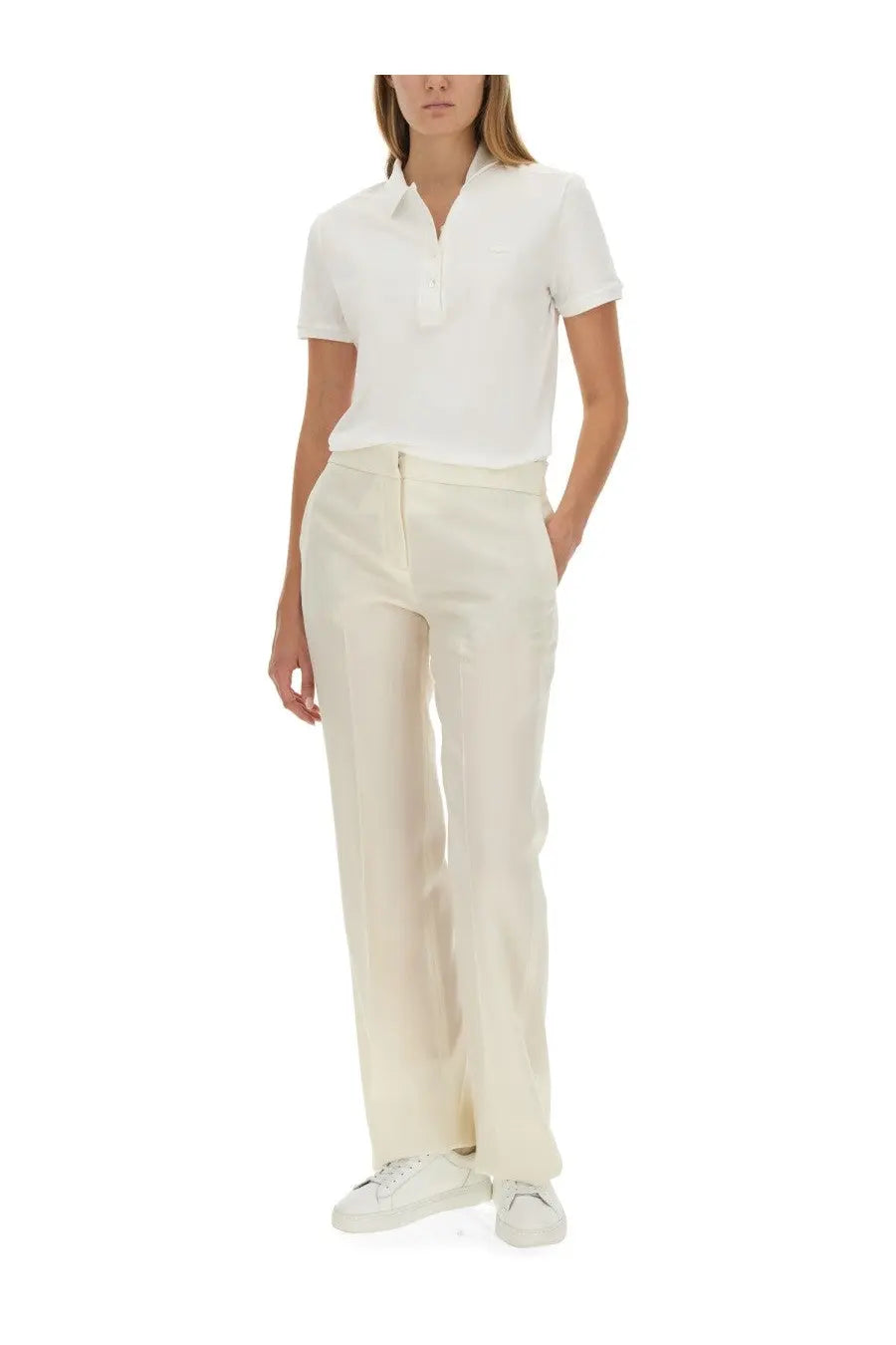 Cream-colored wide-leg trousers with a clean tailored fit paired with Lacoste women’s white polo shirt
