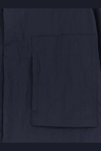 Dark navy fabric pocket with subtle texture and stitched edges on laminar men’s wrinkled nylon jacket blue