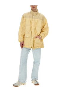 Our Legacy men’s nylon jacket beige is a pale yellow quilted jacket with a high collar and button closures