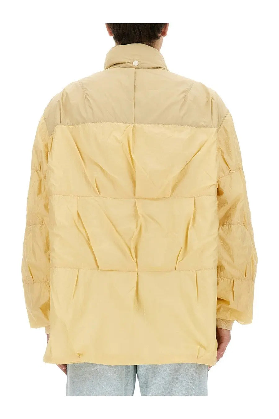 Our Legacy men’s nylon jacket beige features a pale yellow quilted puffer design with a high collar and segmented panels