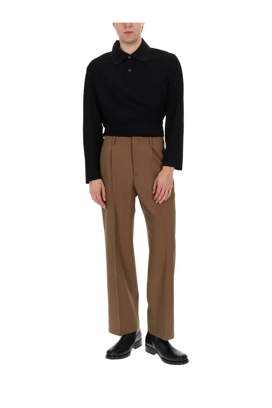 A man wearing our legacy men’s pantalone sartoriale con pieghe brown trousers and a black long-sleeved polo shirt