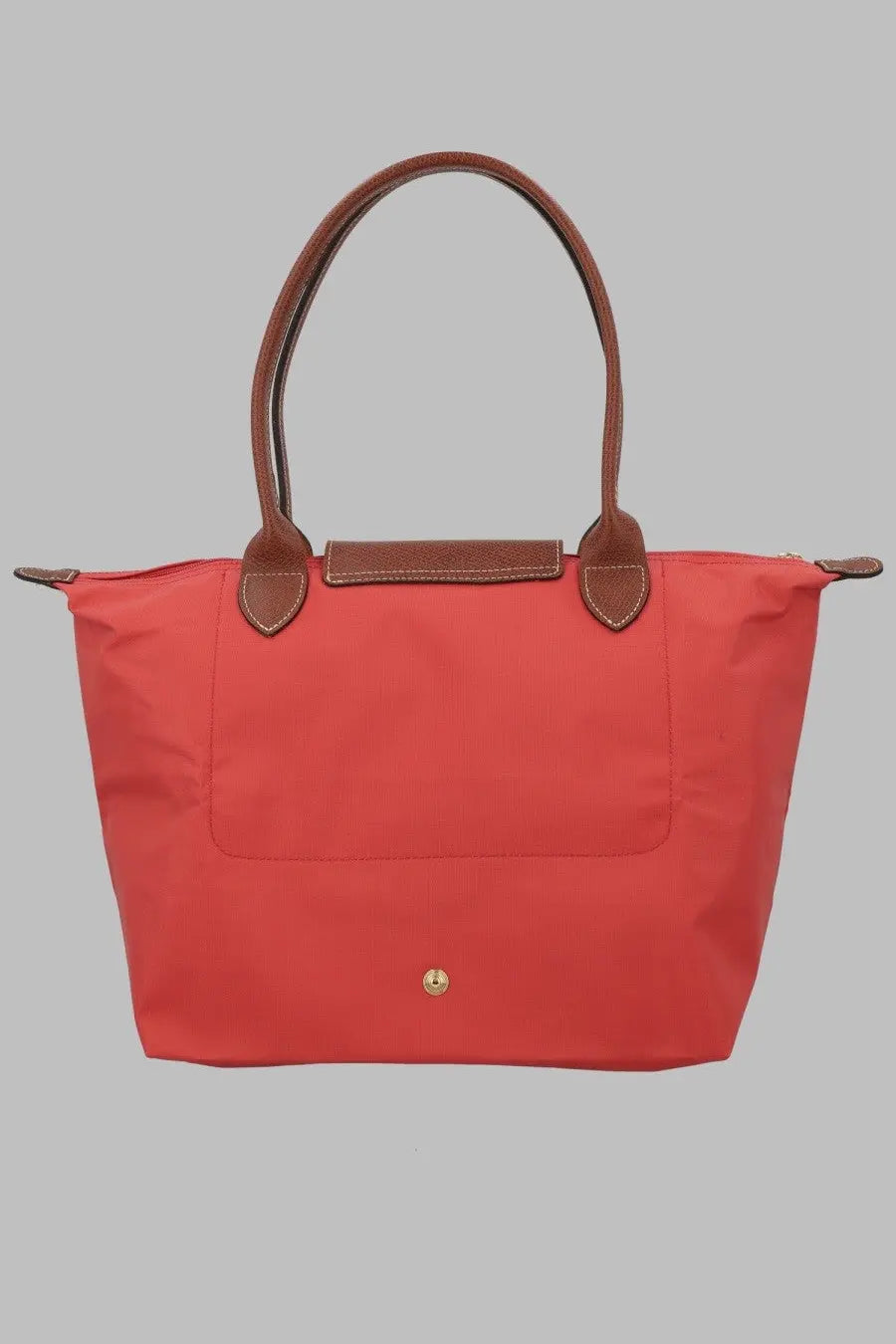 Vibrant coral-red Longchamp Le Pliage tote bag with brown leather handles and trim for women