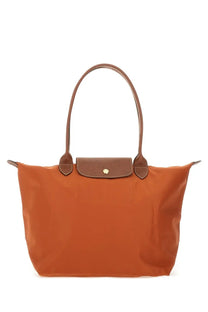 Orange longchamp women’s le pliage large tote bag with brown leather handles and matching flap closure