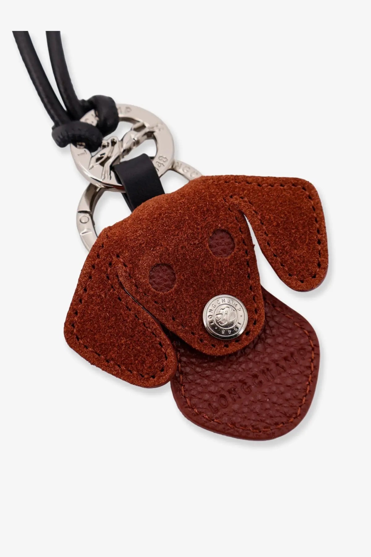 Longchamp women’s leather keychain featuring a brown suede dog shape with silver button and black leather cord