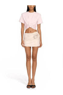 A soft pink short-sleeved top with knotted front detail paired with a beige Magda Butrym women’s denim miniskirt