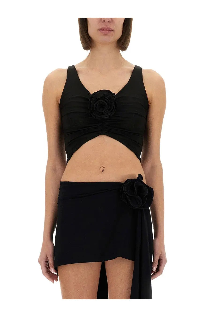 Magda Butrym women’s black satin crop top with ruched fabric and rose embellishment paired with matching skirt