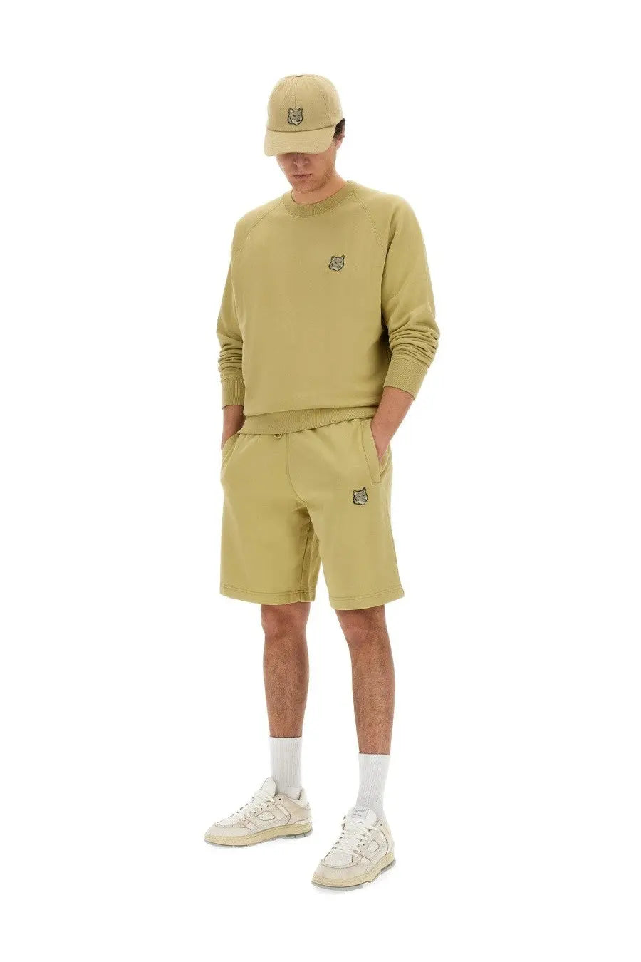 A man wearing beige Maison Kitsuné men’s sweatshirt and bermuda shorts with subtle embroidered tiger logos