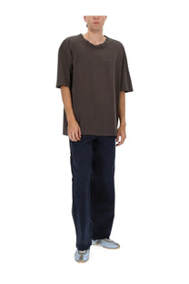 Maison Margiela men’s five pockets jeans in blue paired with a dark gray oversized short-sleeved t-shirt with faded logo