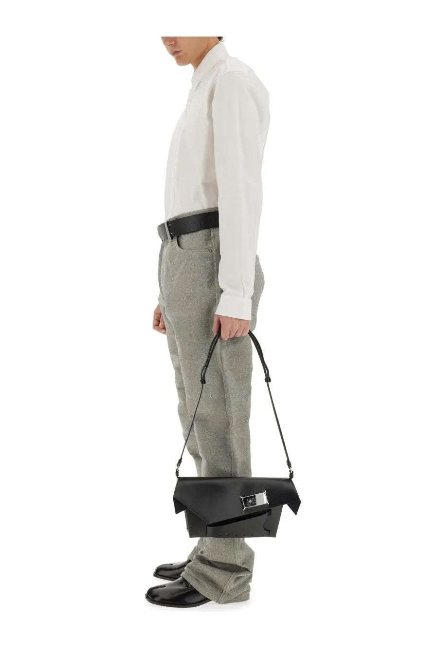 Black leather crossbody bag with sleek angular design and silver hardware paired with maison margiela denim jeans
