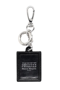 Maison Margiela men’s black leather keychain with silver metal clasp and engraved rectangular logo plaque