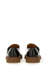 Black patent leather maison margiela men’s mary jane shoes with brown rubber soles and a small bow on the back view